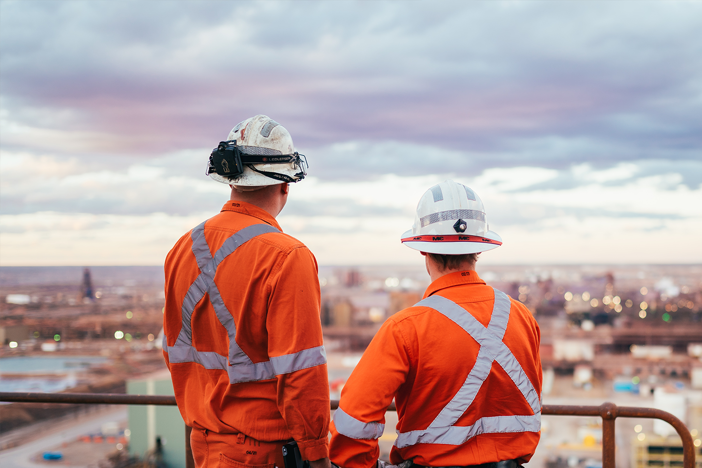 Photo of two workers in hi-vis uniform looking over job site