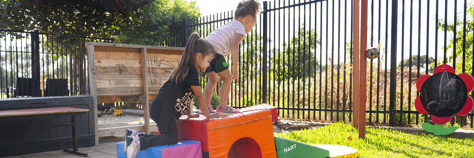 adults helping children climb on obstacle course equipment